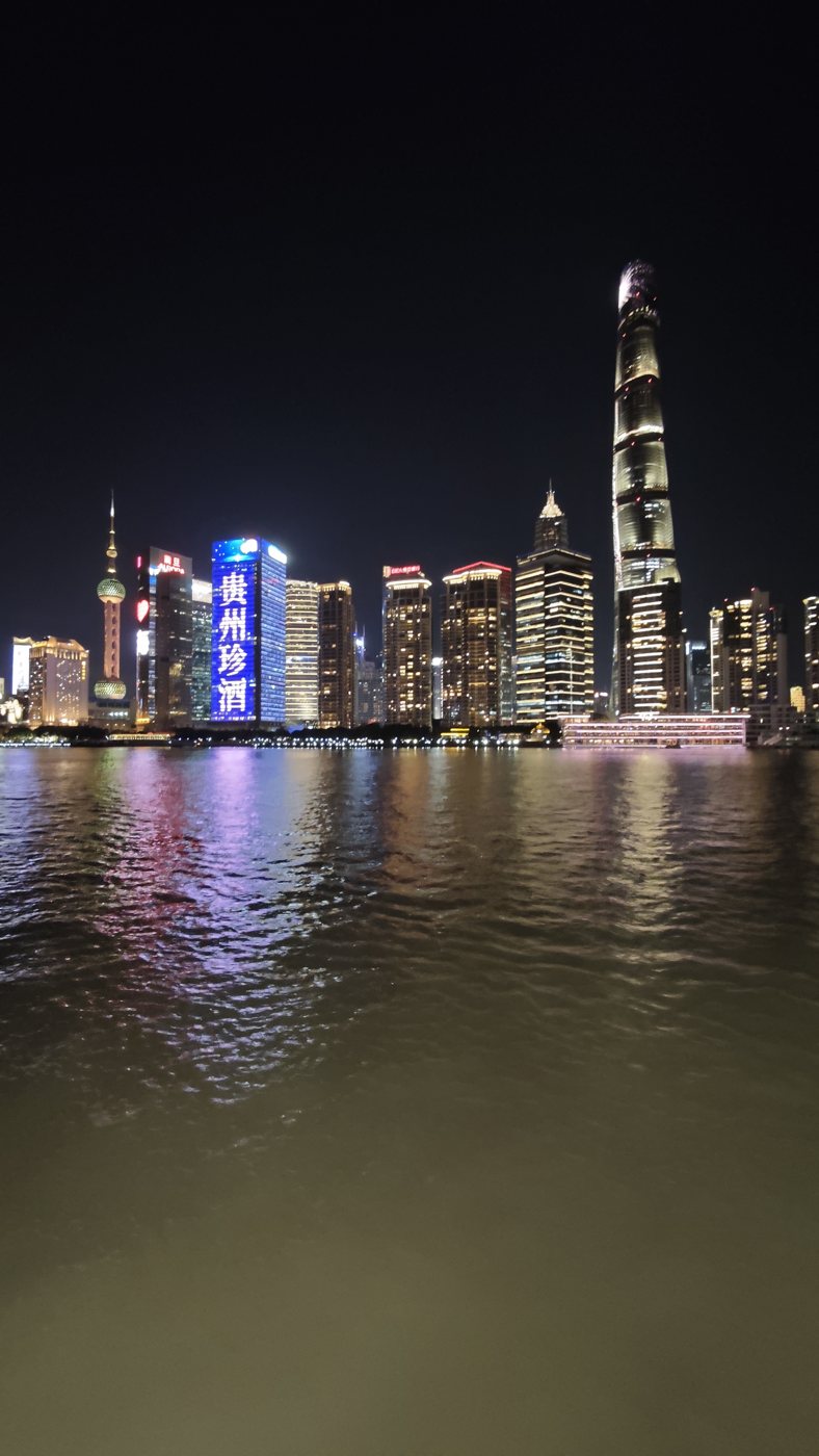 The Pudong skyline across the Huangpu river with gold and pink reflections on the water
