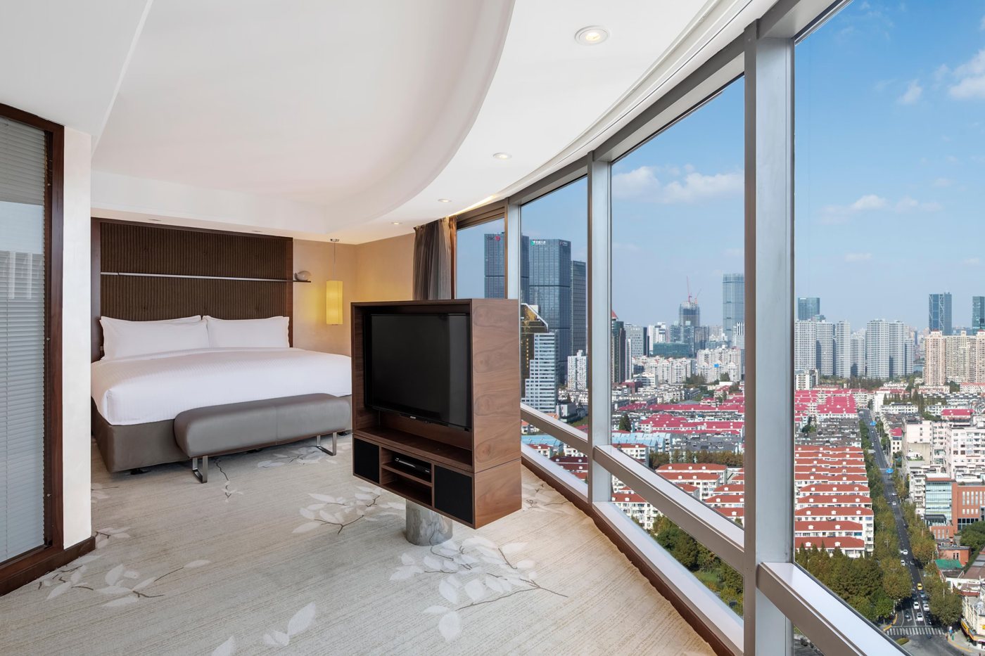 Bedroom of the Diplomatic Suite at InterContinental Shanghai Pudong with a king bed beside a curved glass wall over the city