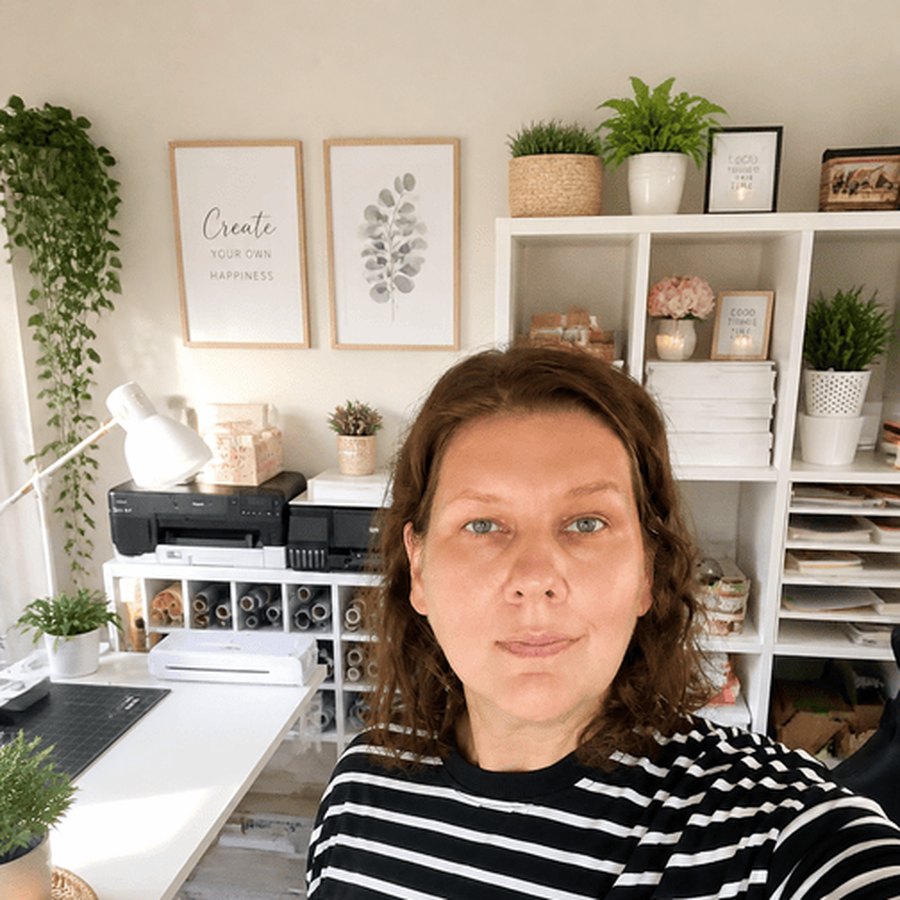 Natali, the author, taking a selfie at her desk with shelves, plants and a printer behind her